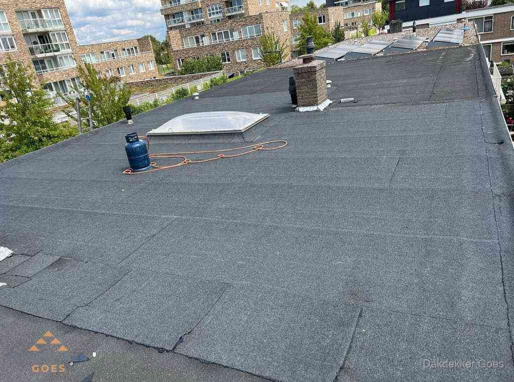 Bitumen dakbedekking op plat dak met lichtkoepel en schoorsteen in Goes