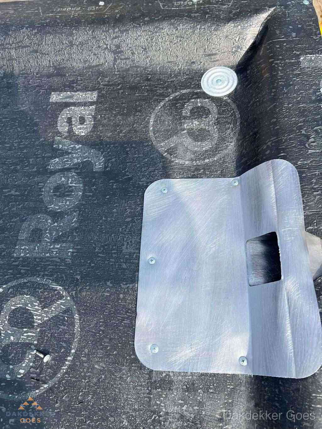 Dakdoorvoer met metalen afvoerplaat op bitumen dak in Goes
