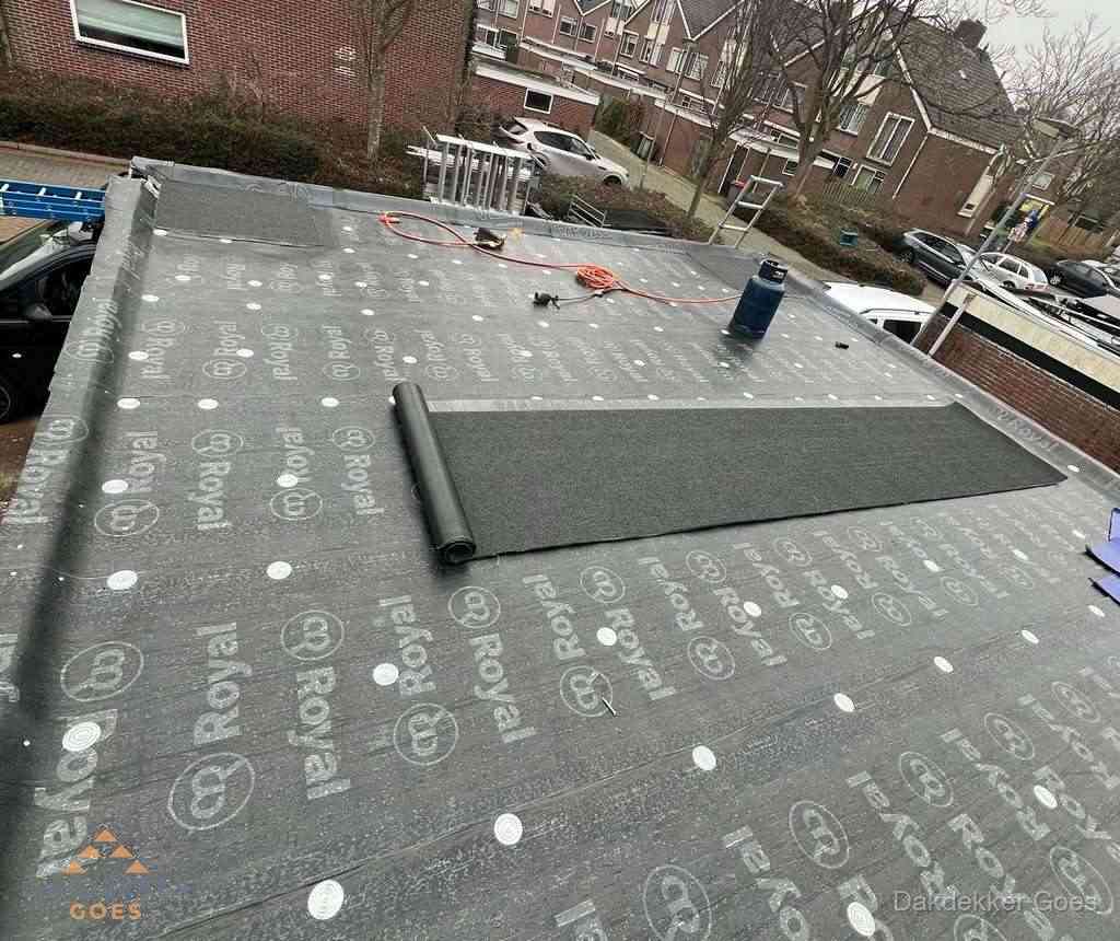 Dakdekker aan het werk met gasbrander op plat bitumen dak in Goes